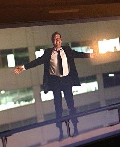Actor Jordan Leigh looks like he's jumping off a building wearing a business suit as he films a stunt shot for a soon-to-be-released film, Stadium Anthems.