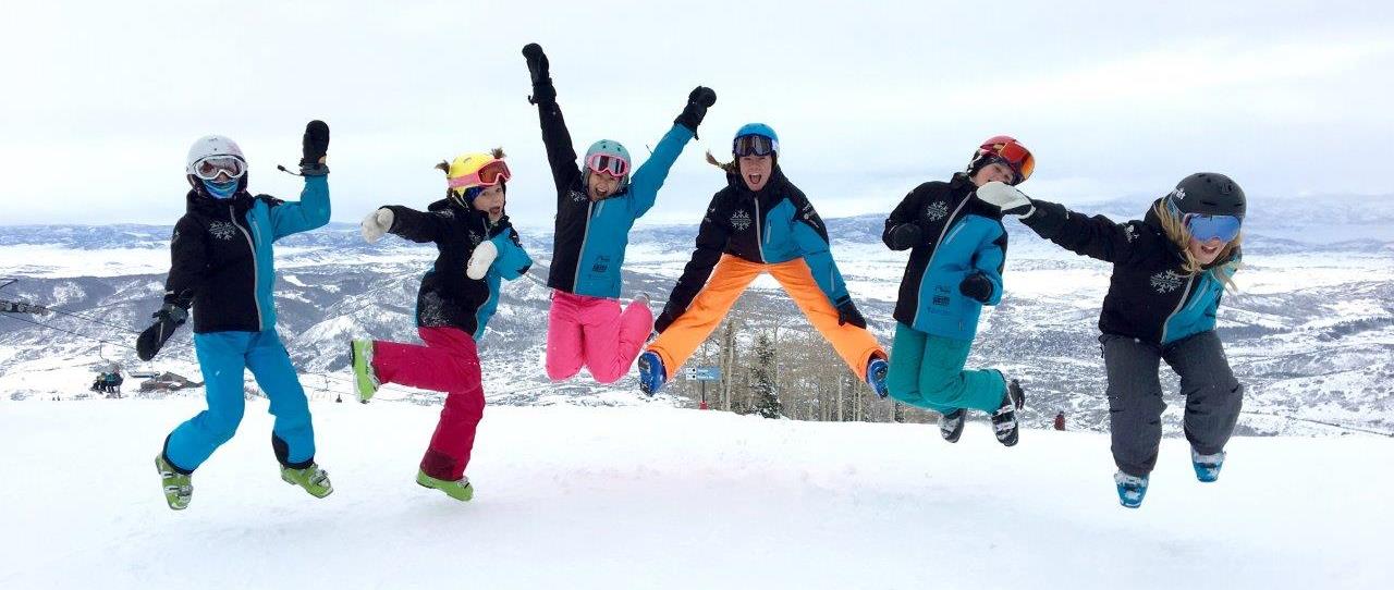 Members of the kids club jumping into the air for a photo shoot on the slopes.