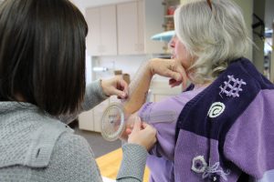 Emily Tjosvold uses a device to measure the flexibility in Barb Wheeler's elbow.