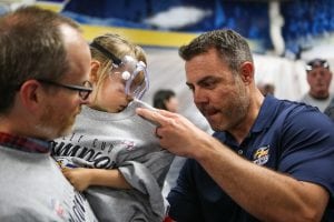A Colorado Eagles coach autographs a fan’s tshirt at a special locker room celebration for UCHealth cancer survivors.