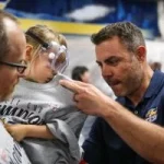 A Colorado Eagles coach autographs a fan’s tshirt at a special locker room celebration for UCHealth cancer survivors.