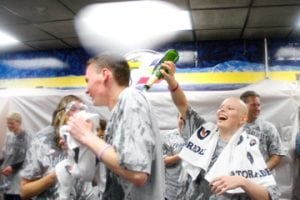 A cancer survivor laughs as she pours sparkling cider on the back of one of her supporters.