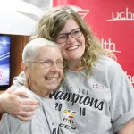 A cancer survivor gets a hug from a member of her care team.
