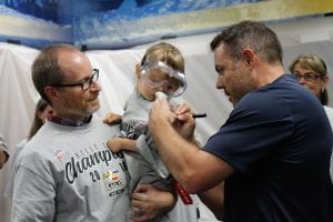 A Colorado Eagles coach autographs a fan’s shirt at a special locker room celebration for UCHealth cancer survivors.