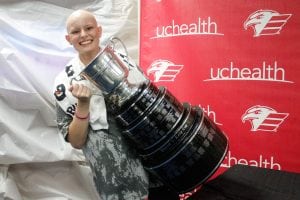A cancer survivor poses with the Kelly Cup championship trophy.