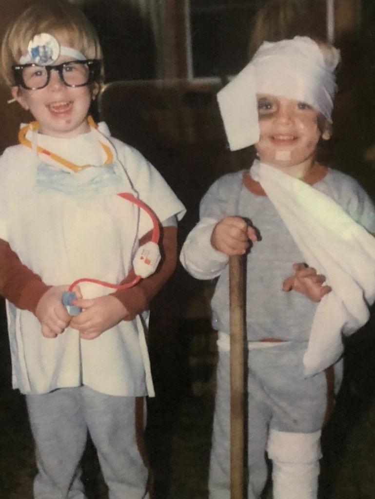 This photo shows two boys who are about 5 or 6. They are twins and are dressed up for Halloween. One is dressed as a doctor and the other is his patient.