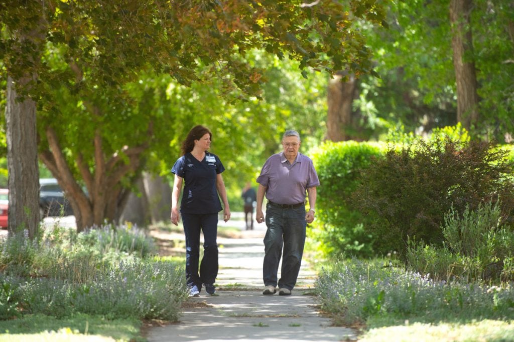 A nurse walking with her patient in a park.