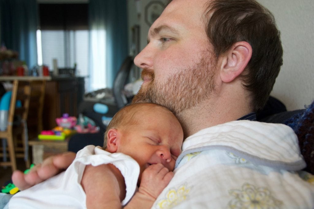 Nate Minarchick holds their second daughter, Riley. She's asleep on his chest.
