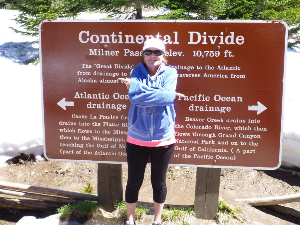 Trisha poses with a Continental Divide sign at the top of a pass. She is new to Colorado and is trying to cope with anxiety after an Alzheimer's diagnosis.