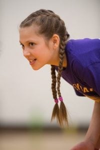 An 11-year-old girl anticipates a volleyball serve from opposing team