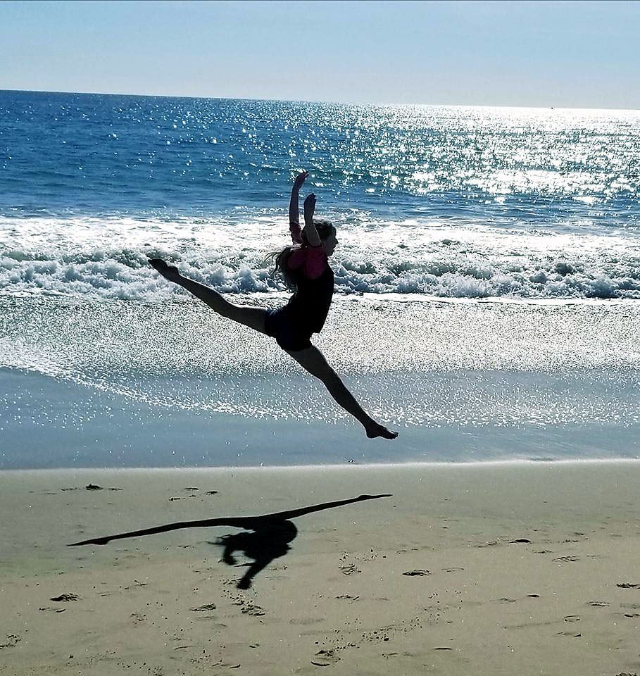 Amelia leaps through the air on a beach.