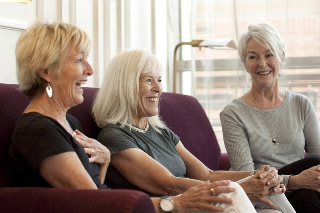 three sisters sitting on the couch laughing.