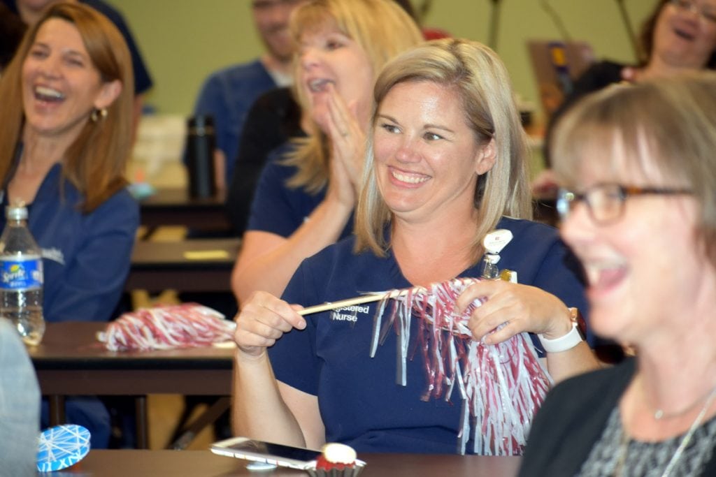 Nurse smiles and holds on to a pom pom as a group gathers to hear the official announcement that Poudre Valley Hospital achieved Magnet status for the fifth time.