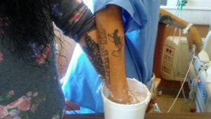 Joe and Antoinette plunge their hands, palm to palm, into a bucket of molding material.