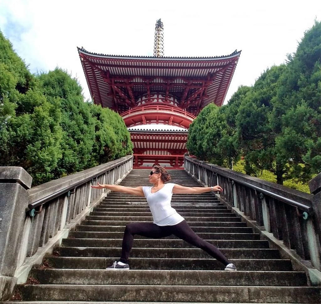 Breast cancer survivor Louisa Drouet does a yoga pose in front of a temple in Asia.