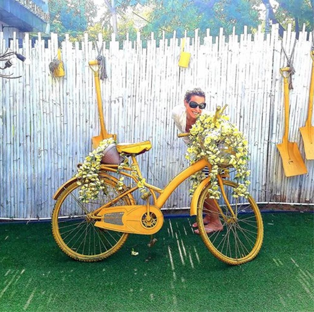 Louisa Drouet poses with a white fence, a yellow bike and other yellow items in a photo from India.