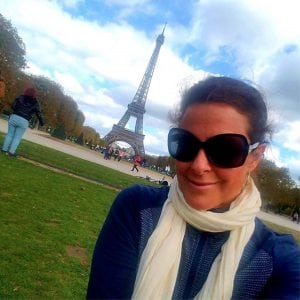 Louisa Drouet poses in Paris with the Eiffel Tour behind her. She is celebrating her breast cancer recovery with a "world victory tour."