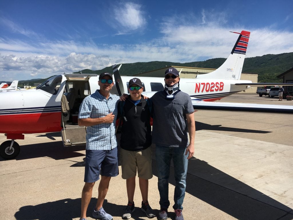 Brian Malek poses with his brother-in-law and nephew in front of an airplane during Brian's recovery from a spinal cord injury..