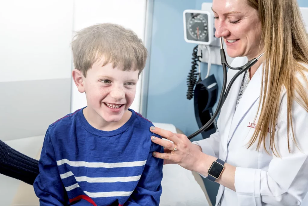 A doctor checks a young boy's lungs with a stethoscope during appointment for a flu shot..