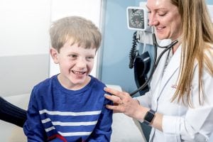 A doctor checks a young boy's lungs with a stethoscope.