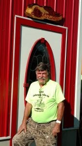 Larry Batman poses before a two-story barn he built in Iliff.