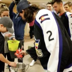 Boy transfers Halloween candy from Kelly Cup trophy to a Halloween trick-or-treating bucket.