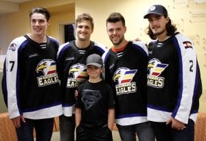 Boy poses for photo with four pro hockey players in a hospital hallway.