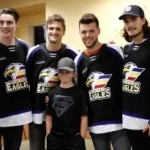 Boy poses for photo with four pro hockey players in a hospital hallway.