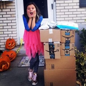 Marlie with a surprised face and a stack of boxes on her doorstep.