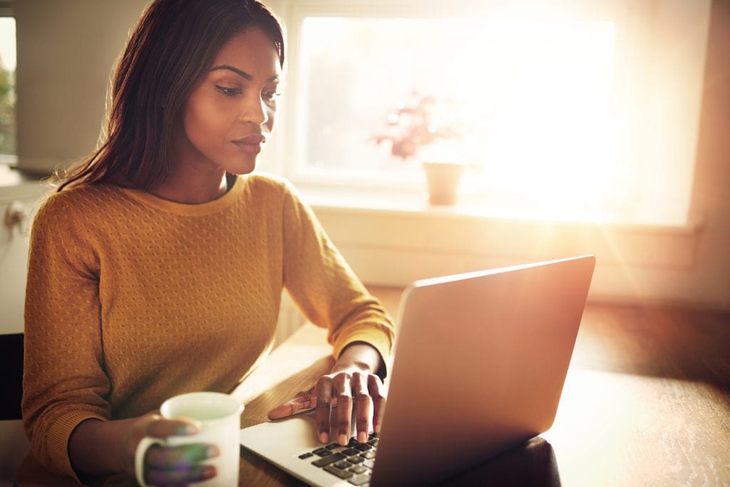 A woman who looks serious is checking something on her laptop.