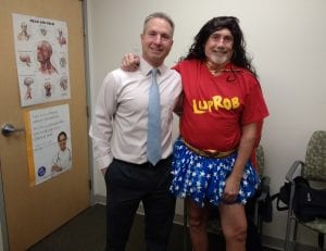 Dr. Petit and Rob, who is dressed in red shit and blue-starred tutu, and a black wig