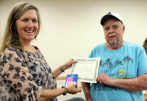 Julie hands Ray a completion certificate from the class.