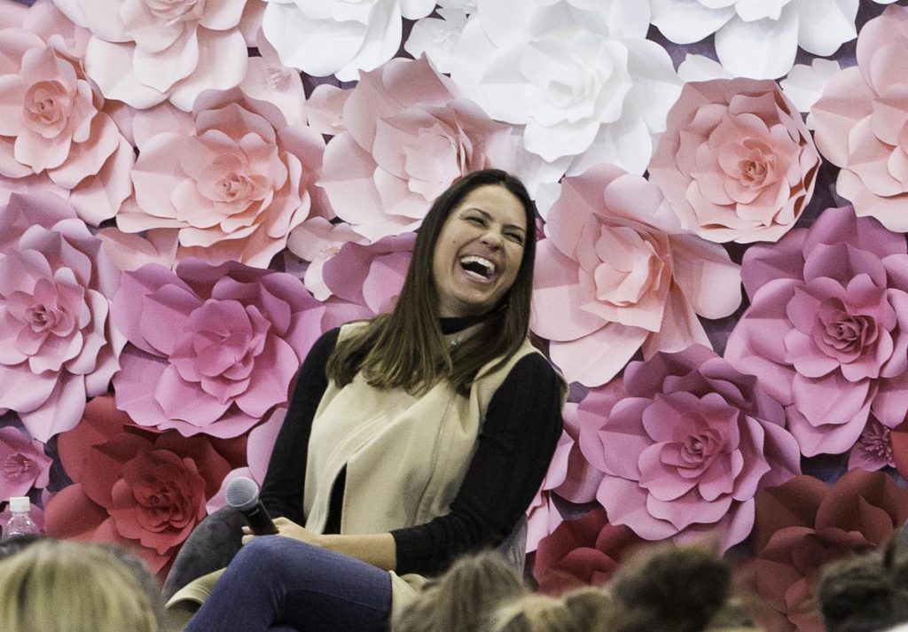 Softball Olympian Jessica Mendoza smiles with a floral background during evre, a UCHealth women's health event.