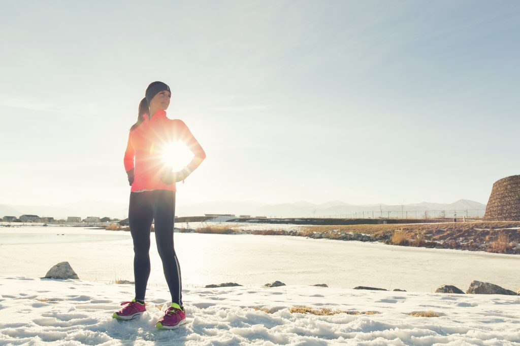A woman stands oustide on a sunny winter morning.
