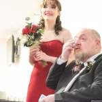 father wipes tears while daughter holds wedding flowers