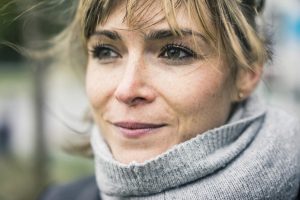 A middle-aged woman outside, wearing a turtlenext sweater.