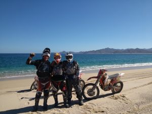 Three dirt bike riders pause their ride for a photo on the beach.