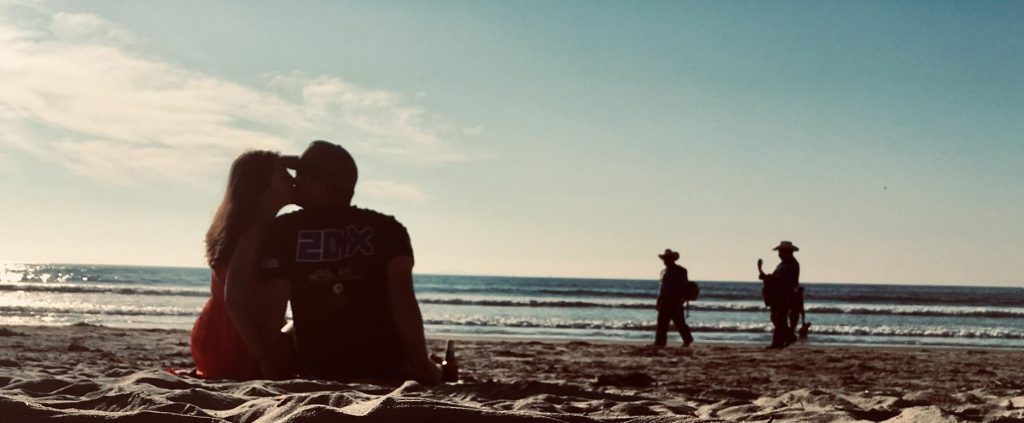 Chris Welch and his fiance, Dominique Janku, share a kiss on the beach.