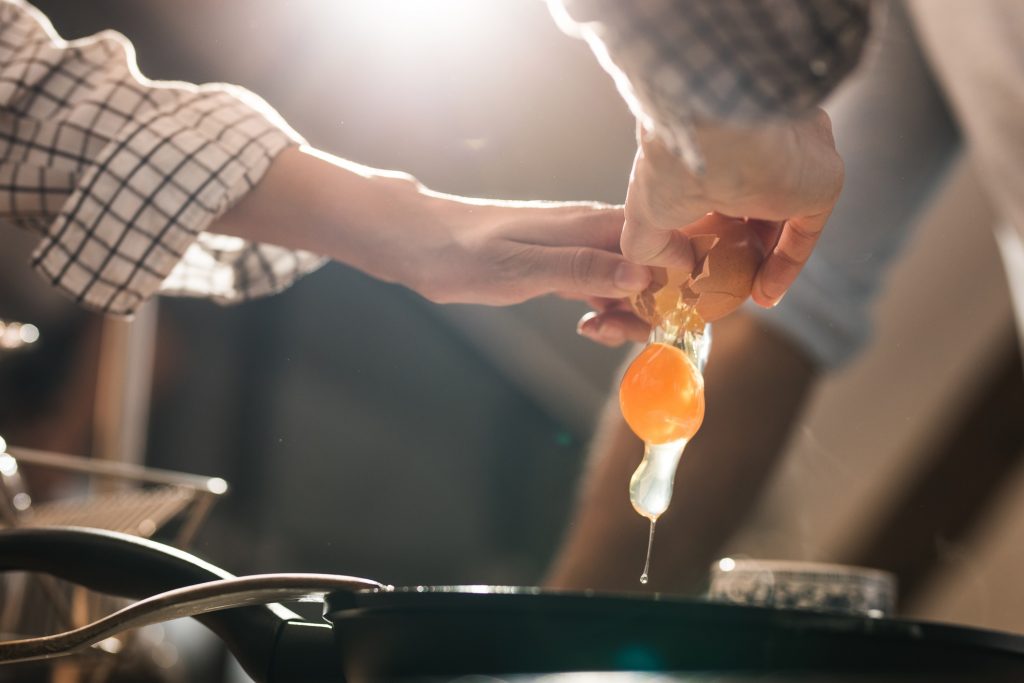 A person cracks an egg into a skillet.