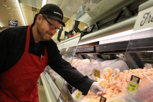 Carey Robinson adjusts a price sign at the seafood counter in the grocery store where he works.