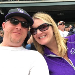 A couple smiles for a selfie at a Colorado Rockies game.