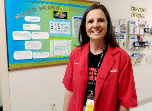 Sam in her red volunteer uniform in the neurology unit hallway