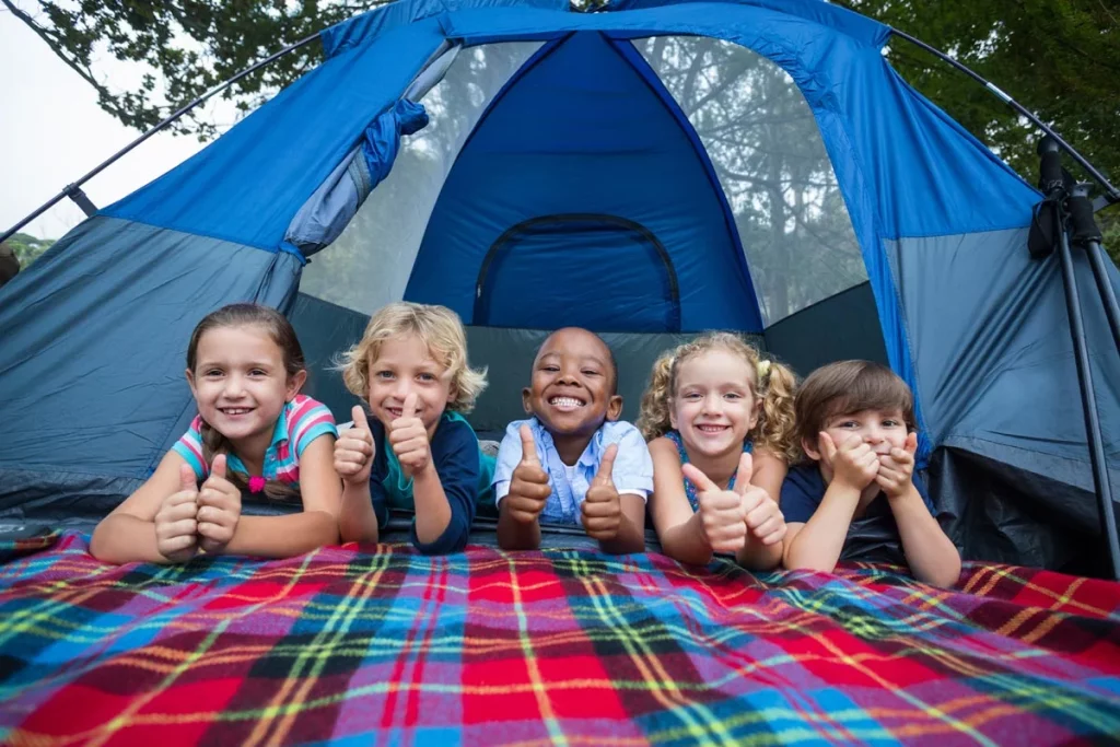 Children lay on their bellies in front of a tent