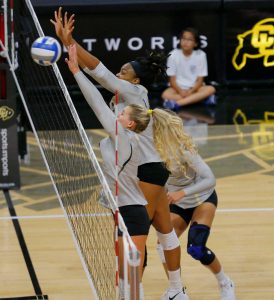 volleyball players blocking at the net, including Abu in a game after her meniscus surgery.