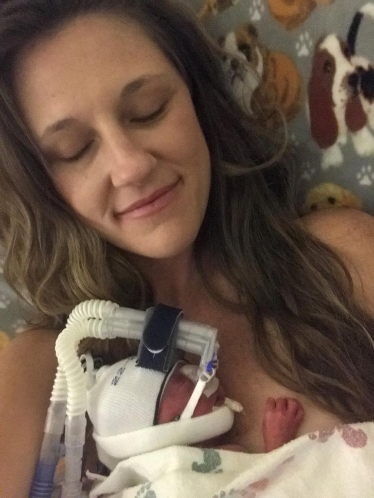 A preemie baby nestles into his Mom's chest.
