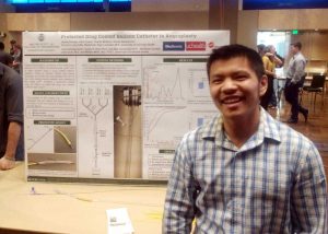 Student stands in front of his poster at the fair.