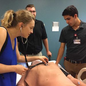 student listens to heartbeat on a simulation dummy