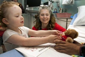 Child reaches for teddy bear.
