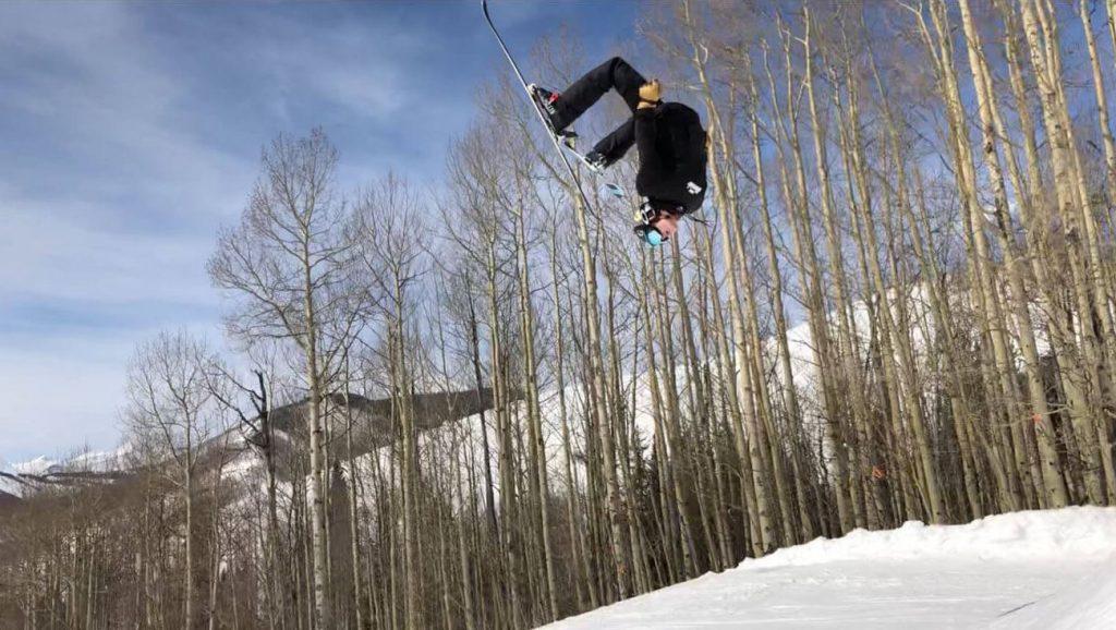 A young man does a back flip on skis
