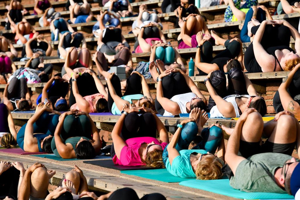 People on mats doing yoga at Red Rocks Amphitheater.